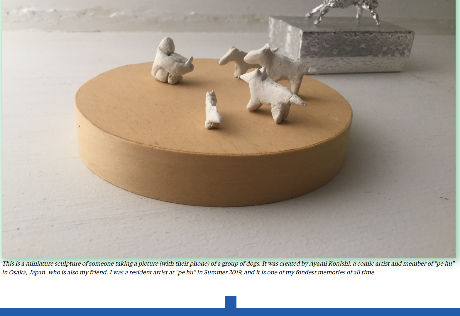 a miniature sculpture of someone taking a picture (with their phone) of a group of dogs. It was created by Ayami Konishi, a comic artist and member of pe hu in Osaka, Japan